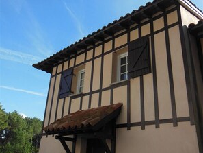Ein traditionelles Fachwerkhäuschen mit geneigtem Dach und zwei Fenstern.