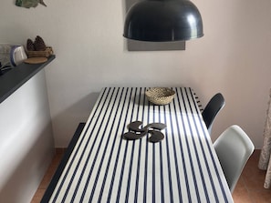 Ein Essbereich mit gestreifter Tischdecke, einem Korb und einer Sonnenbrille auf dem Tisch.