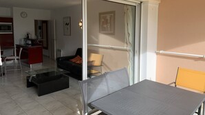 Eine moderne Wohnung mit Essbereich, einer Küche, einem Wohnzimmer mit Sofa und einer Glastür, die auf einen Balkon führt.