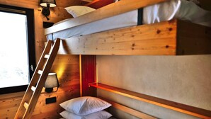 Ein Etagenbett mit einer Leiter, ein Nachttisch und eine Wandlampe.