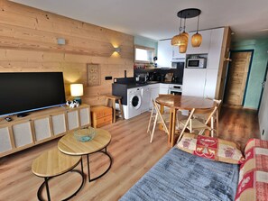 A compact living space with a TV, sofa, dining table, kitchen area, and laundry facilities. - Convenient studio, ski-in/ski-out - 4 guests (Le Grand-Bornand)