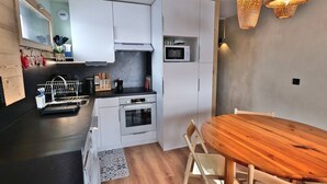 Eine kompakte Küche mit weißen Schränken, einer Mikrowelle und einem Holzespeisetisch.