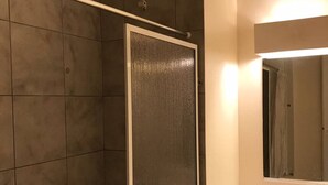 Ein Badezimmer mit Dusche, Waschbecken und Spiegel.