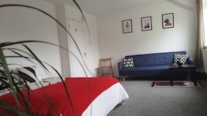 Een slaapkamer met een bed, een blauwe bank, een stoel en drie ingelijste foto's aan de muur.