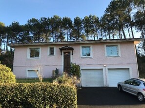 Una casa a due piani con garage, ingresso e vialetto.