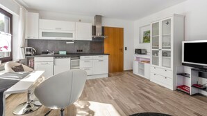 Een moderne keuken met witte kasten, een houten deur en een ingebouwde televisie.