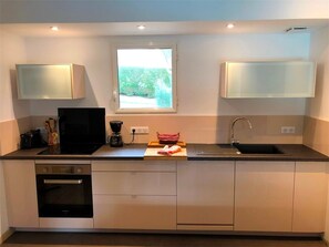 Eine moderne Küche mit Backofen, Kaffeemaschine, einem Fenster mit Blick und einem Spülbecken.