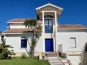 Ein zweistöckiges Haus mit blauer Tür, Satellitenschüssel und Ziegeldach.