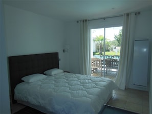 Ein Schlafzimmer mit Bett, Fenster und Blick ins Freie.