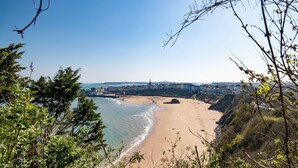 Eine Küstenlandschaft mit Strand, einer Stadt in der Ferne und umgebender Vegetation.