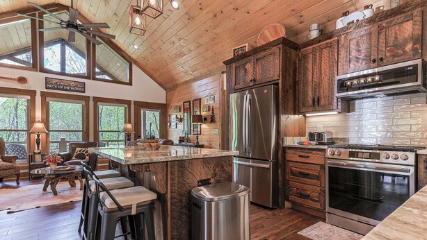 A kitchen with wooden cabinets, a stainless steel refrigerator, and a built-in oven. - Creekside Solace by Mountain Oasis | Near Aska Adventure Area w/Toccoa River Access (Blue Ridge)