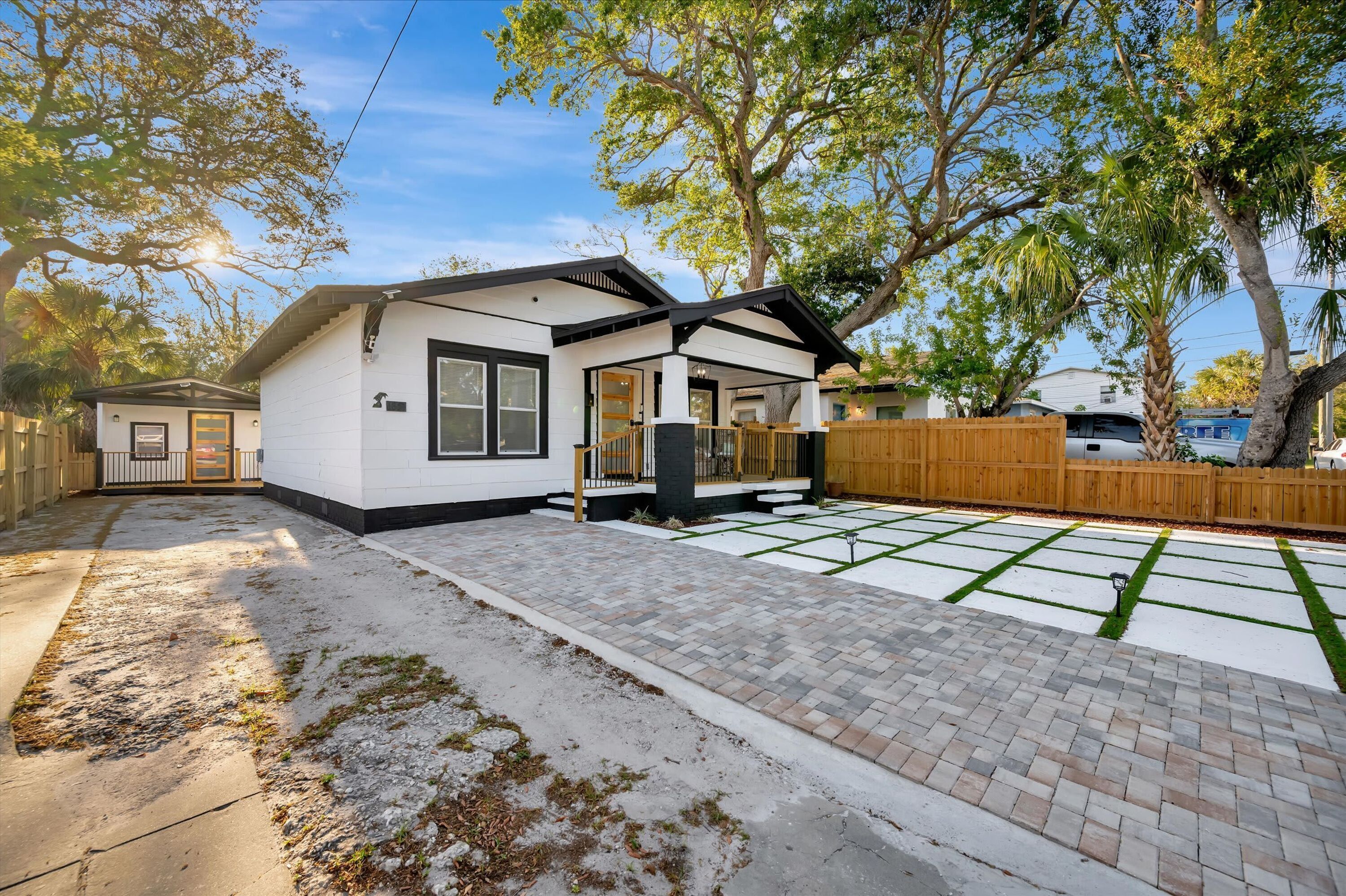 Una casa moderna con un patio, un jardín cercado y una terraza de madera.