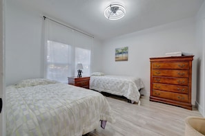 A bedroom with two beds, a wooden dresser, a ceiling fan, and a painting on the wall. - Modern Oasis Home 10 Min to St Pete Beach (St. Petersburg)