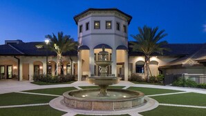 A courtyard with a central fountain, a tower-like structure, and a building with arched windows. - 4BR Resort Home Pool Gym Disney Minutes Away (Davenport)
