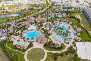 An aerial view of a resort with multiple swimming pools, a central pavilion, and a surrounding road. - 4BR Resort Home Pool Gym Disney Minutes Away (Davenport)
