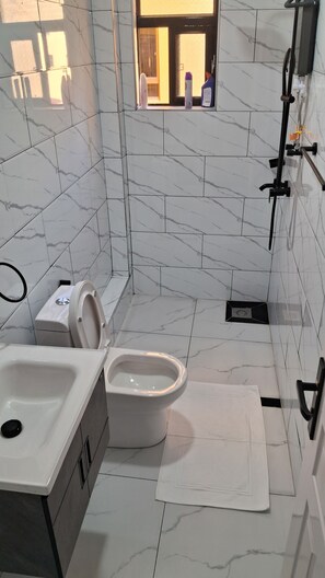 Casa de banho com sanita, bidé e lavatório, revestida a mármore branco.