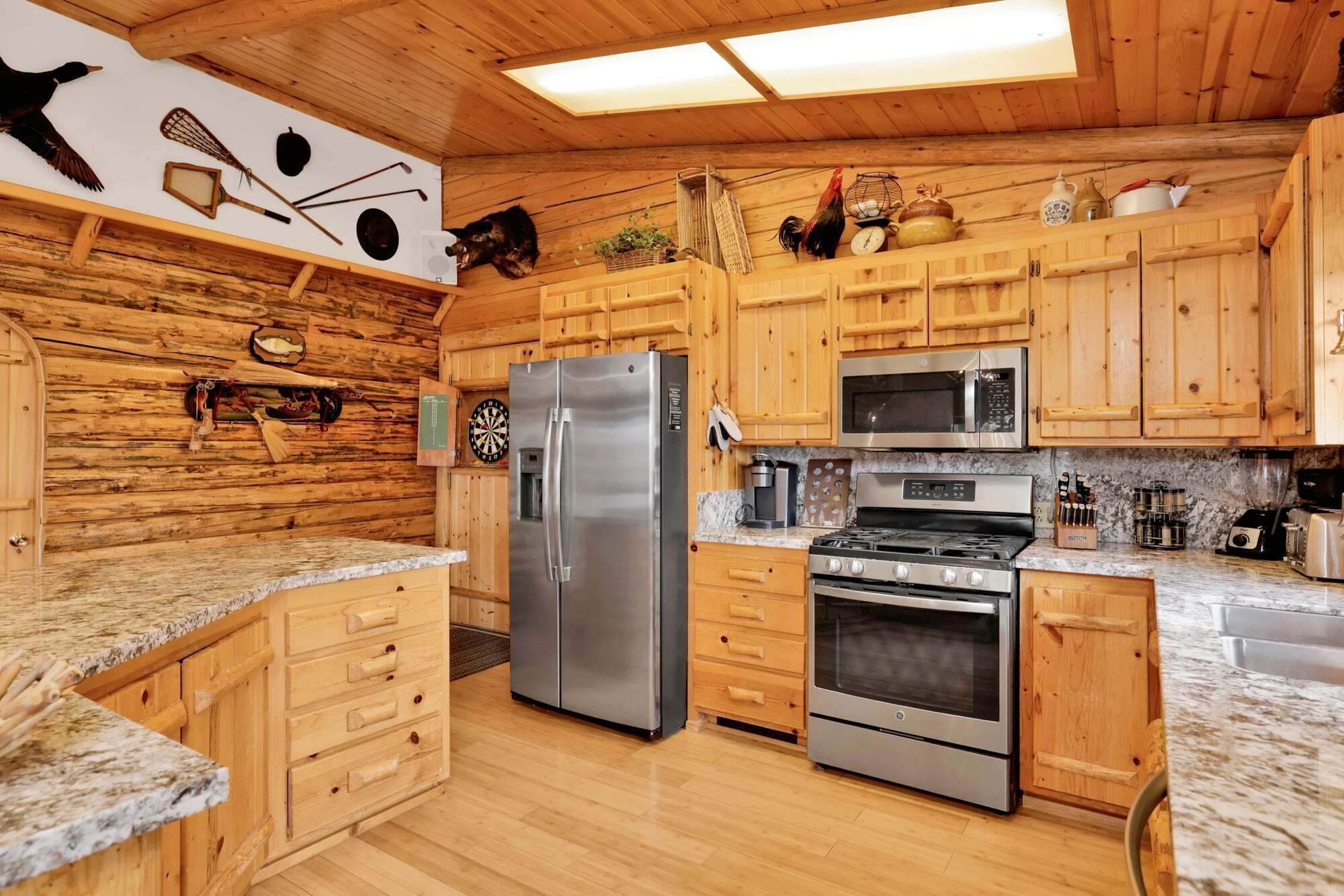 A kitchen with wooden cabinets, a stainless steel refrigerator, an oven, a microwave, and a gas stove.