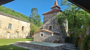 A courtyard with a stone building, a pool, and a large tree. - Gîte le pigeonnier de la jalberterie (Varen)