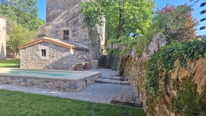 A stone building with a small window, a pool, and a garden area. - Gîte le pigeonnier de la jalberterie (Varen)