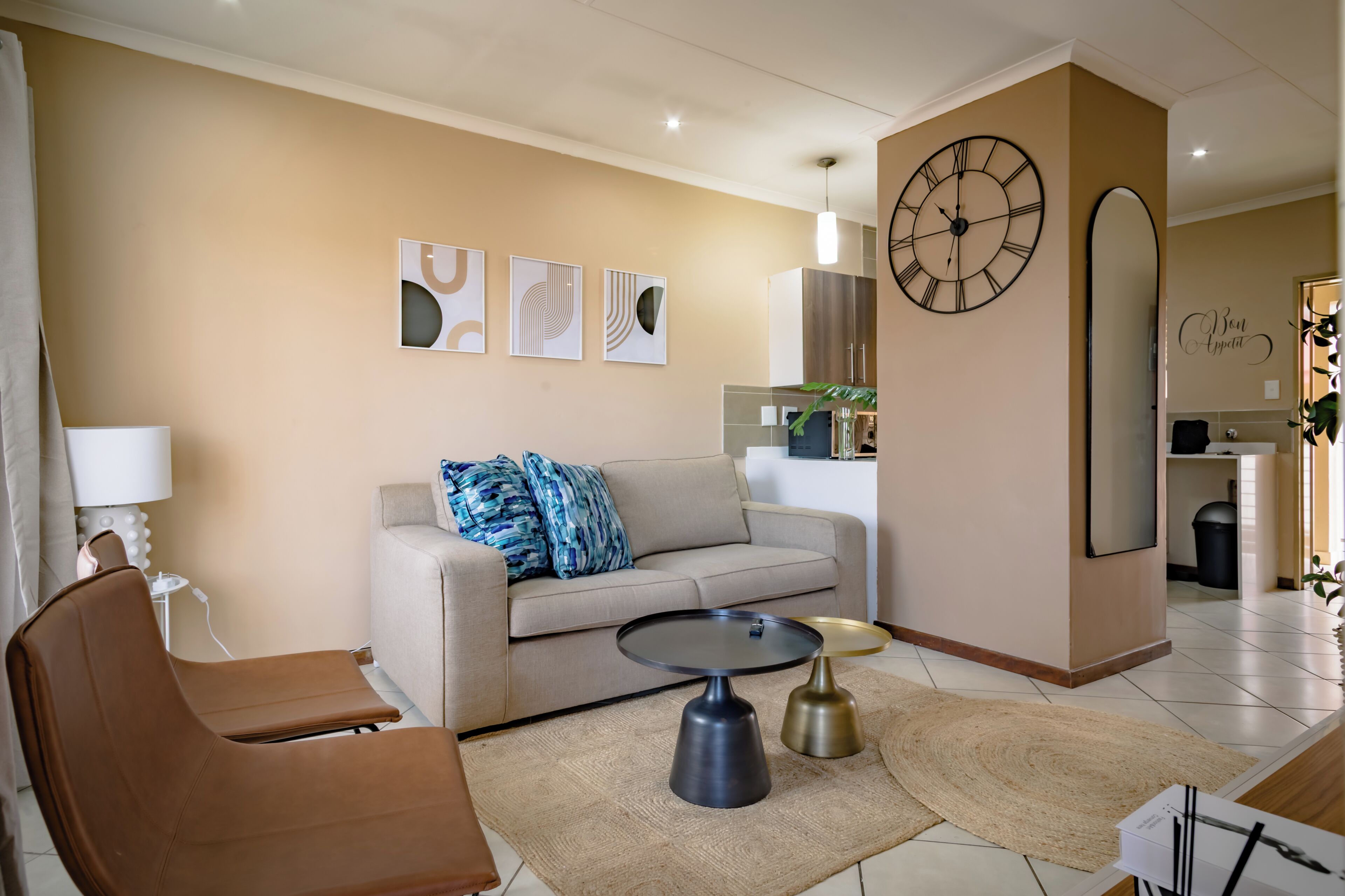 Un salon comprenant un canapé, une table basse, un fauteuil et une horloge murale.