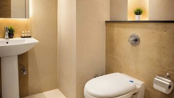 A bathroom with a white sink, toilet, and a small shelf with toiletries.