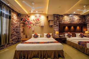 Habitación de hotel con una cama grande, dos mesitas de noche, un ventilador de techo y una pared de acento de piedra.