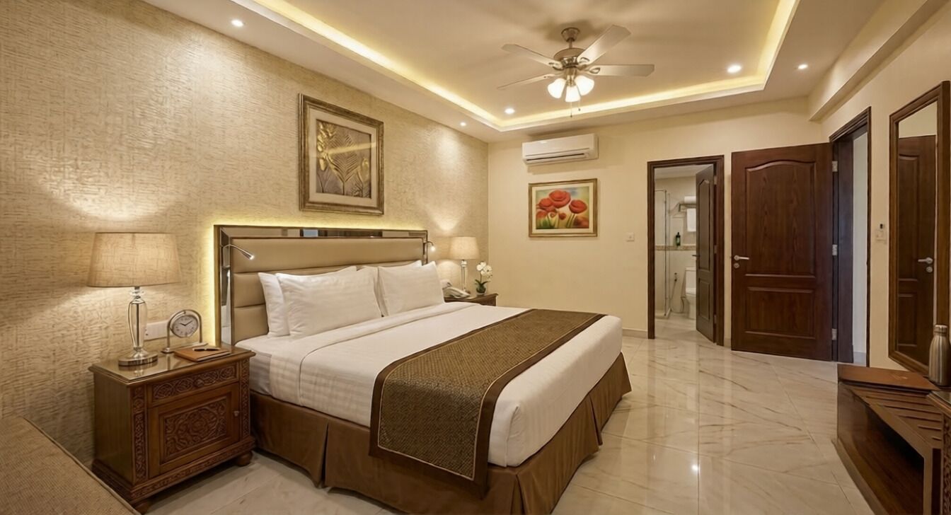 A bedroom with a bed, bedside table, lamp, and artwork on the wall.