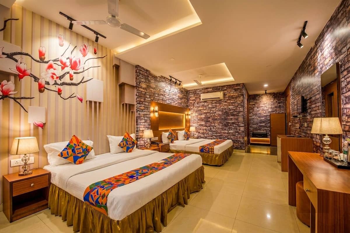 A hotel room with two beds, a desk, a mirror, and a wall with a floral mural.