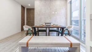 A modern dining area with a rectangular table, four chairs, and a bench. - NOK Cozy 2 BR at Usaquen (Bogotá)