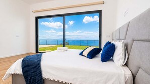 Quarto com uma cama grande, vista para o mar e varanda.