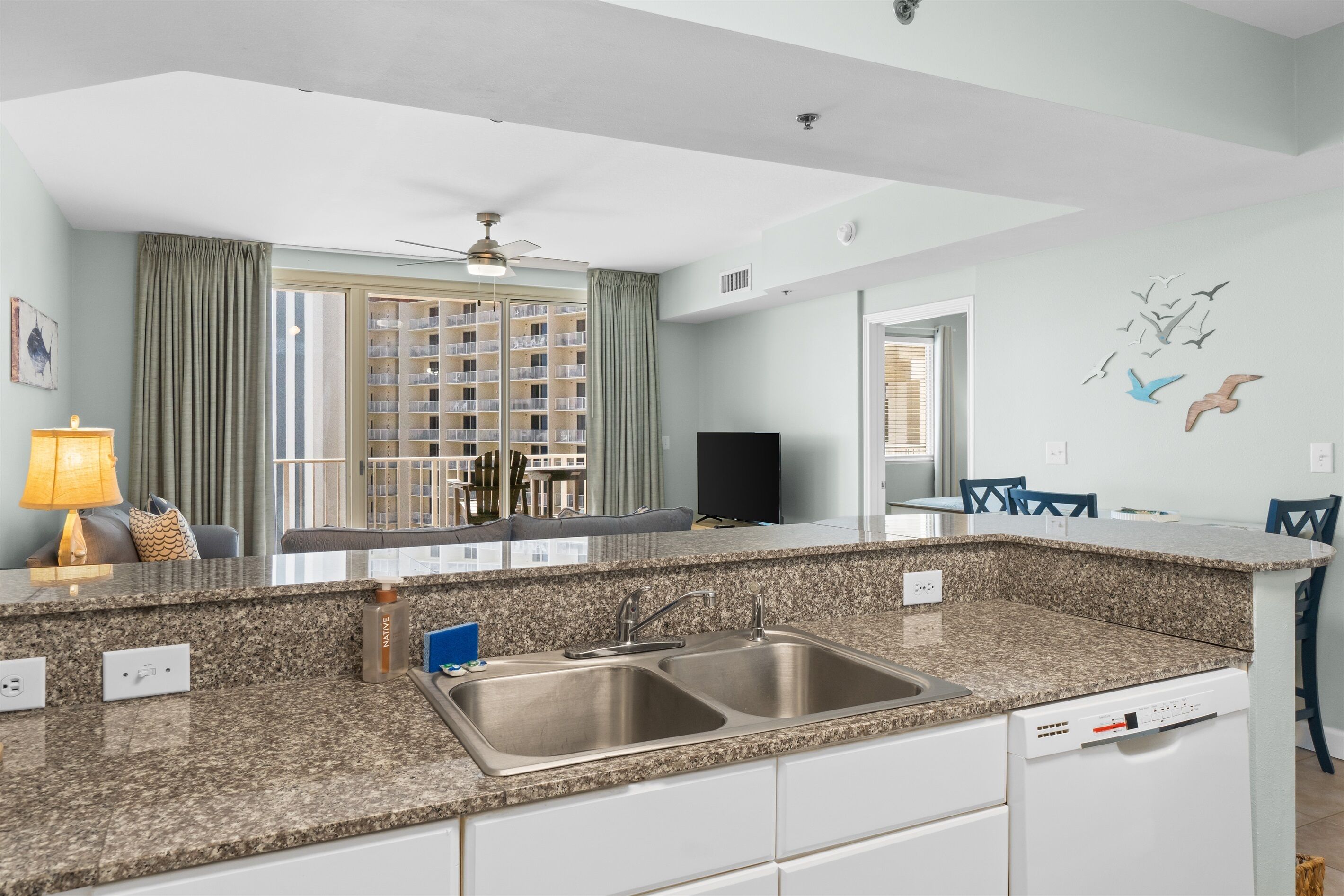 Una cocina moderna con encimeras de granito, un lavabo doble y lavavajillas.