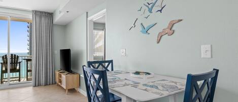Un comedor con mesa, sillas y televisor. Hay un balcón con vistas.