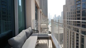 Ein Balkon mit einer Couch und einem Esstisch, mit Blick auf eine Skyline mit Hochhäusern.