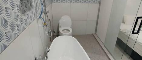 A bathroom with a bathtub, toilet, and glass shower enclosure.