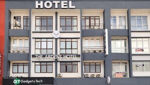 Ein mehrstöckiges Hotel mit einer Fassade, auf der 'HOTEL' und 'THE ARDEN'S HOTEL' stehen. Unter dem Eingang befindet sich ein Geschäft mit dem Schild 'Gadget & Tech'. Vor dem Hotel sind mehrere Autos geparkt.