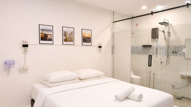 Ein Hotelzimmer mit einem Bett, einer Dusche und drei gerahmten Bildern an der Wand.