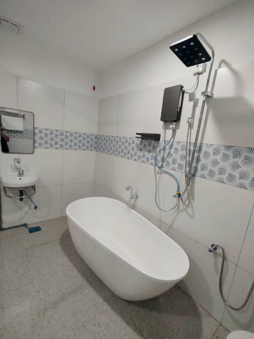 Un baño con una bañera independiente, un cabezal de ducha empotrado y un lavabo con espejo.