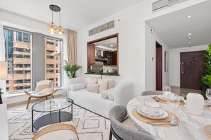Ein modernes Wohnzimmer mit einem Glastisch, einer Couch und einem Essbereich mit einem mit Tischgedecken für vier Personen gedeckten Marmor-Esstisch.