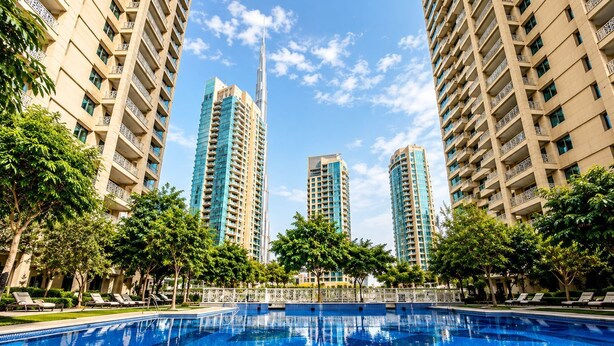 A swimming pool surrounded by tall residential buildings with balconies. - Gala Guests - 29 Boulevard Residences (Dubai)