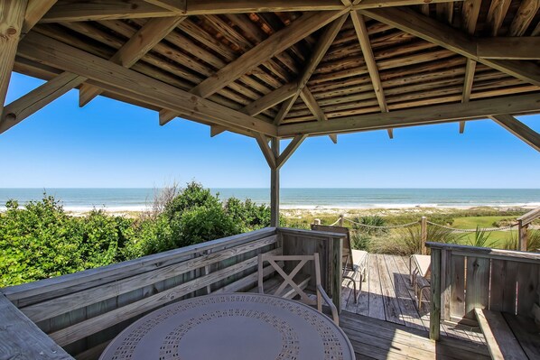 A wooden deck with a view of the beach and ocean.