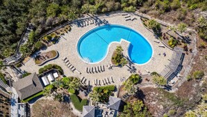 An aerial view of a resort with a large circular pool, sun loungers, and a small building. - Oceanside with Pool, Hear the waves! Beach Walker Villas (Fernandina Beach)