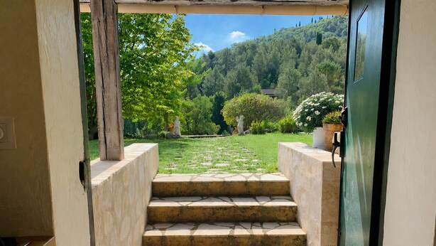 A set of stone steps leading to a door, surrounded by a garden with a view of a forested hill. - Charming Private Cottage with Garden & Parking in Bar-sur-Loup (Le Bar-sur-Loup)