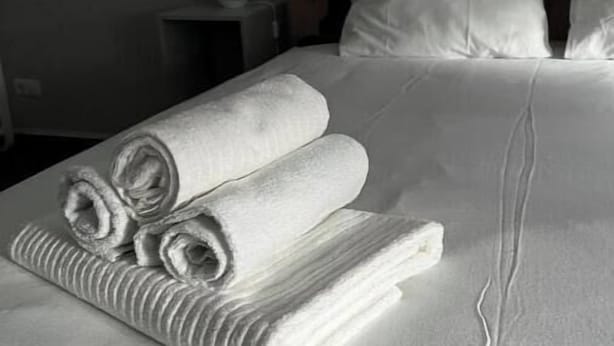 A neatly made bed with white linens, a wooden headboard, and a small bedside table with a lamp. - A little dream in the heart of Innsbruck: Stylish apartment near the old town (Innsbruck)