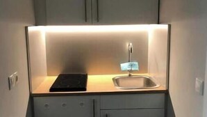 A compact kitchen with a built-in stove, a sink, and cabinets. - A little dream in the heart of Innsbruck: Stylish apartment near the old town (Innsbruck)