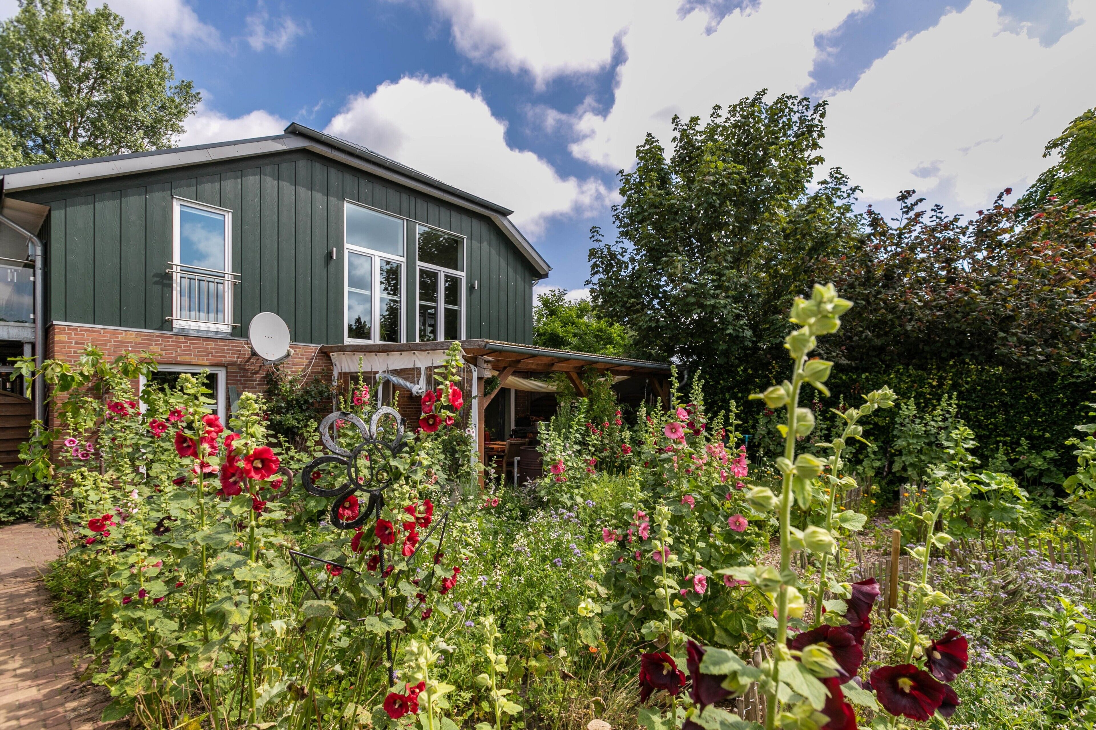 Ein Haus mit Garten, Satellitenschüssel und überdachter Veranda.