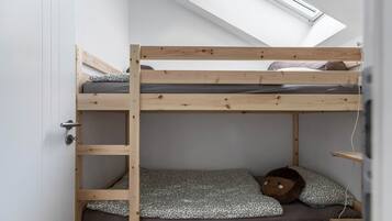 A bunk bed with a skylight above, a door on the left, and a shelf on the right.