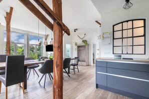 Uma cozinha moderna com uma ilha grande, vigas de madeira e vista para o exterior.