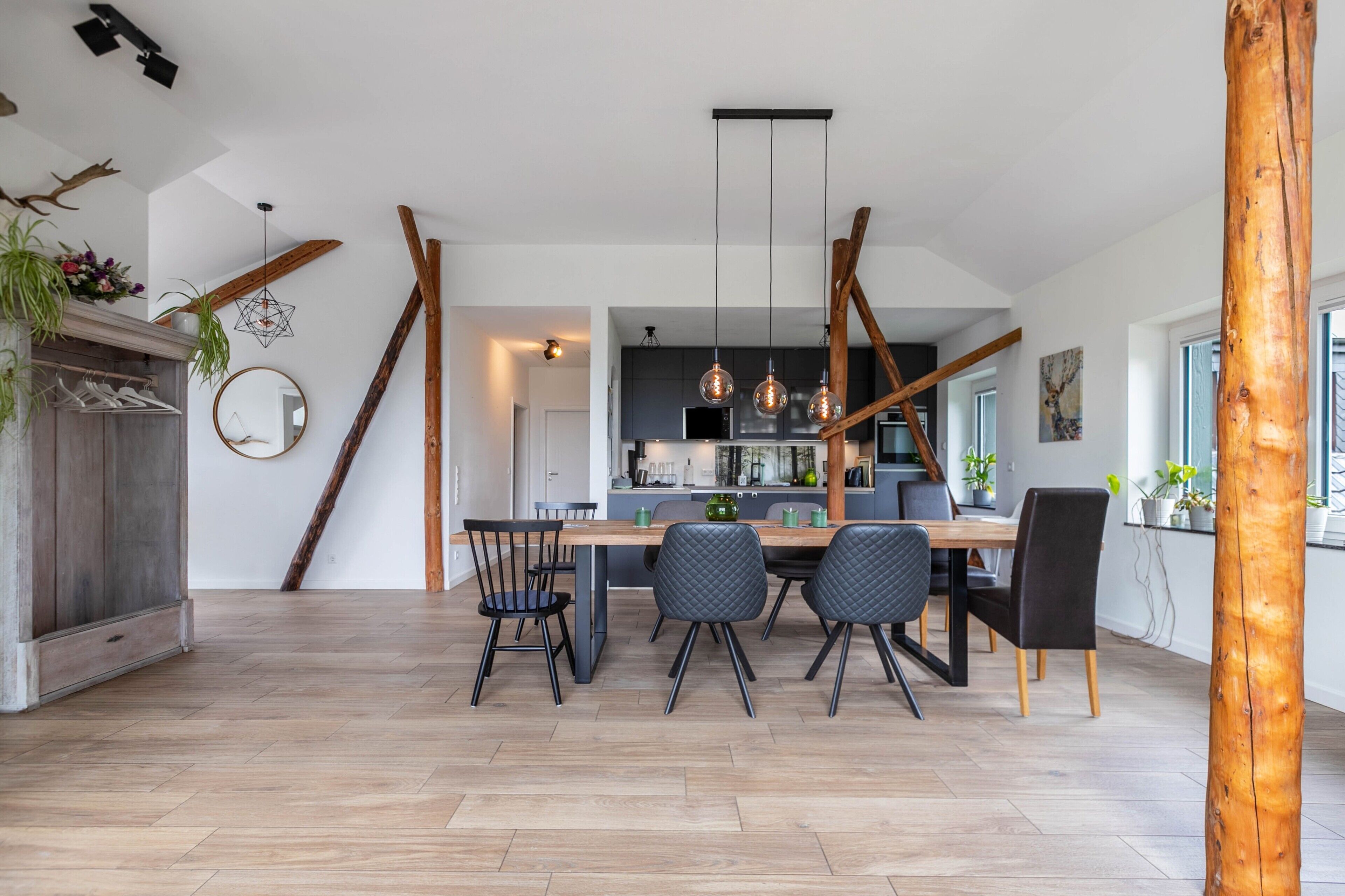 A modern kitchen with a central island, pendant lighting, and a dining area with a wooden table and chairs.