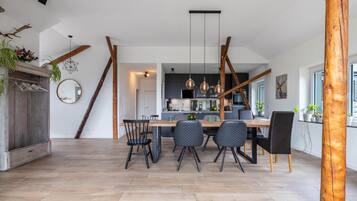A modern kitchen with a central island, pendant lighting, and a dining area with a wooden table and chairs.