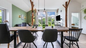 A dining area with a large wooden table, black chairs, and pendant lights. - Apartment "Hof Wuushöh" with Shared Garden, Balcony, and Wi-Fi (Stolk)